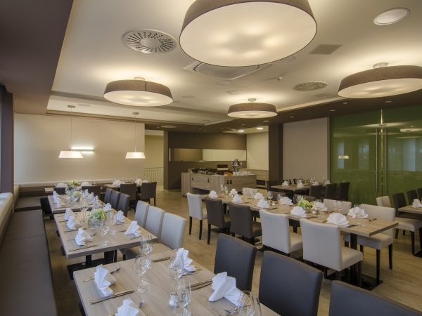 Helles Event Restaurant mit gedeckten Tischen und Blick auf das Buffet sowie den Eingang